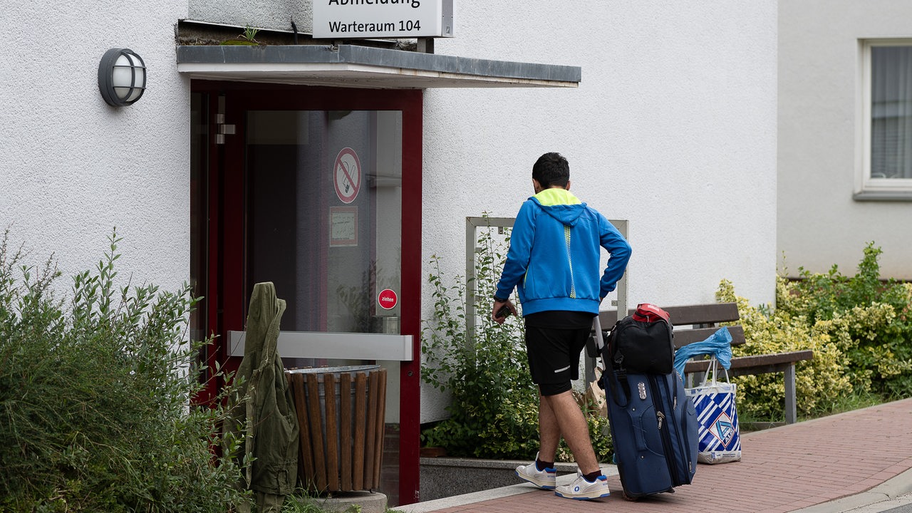 Ein Geflüchteter geht mit einem Koffer in die Anmeldung der Landesaufnahmebehörde Niedersachsen am Standort Grenzdurchgangslager Friedland. 