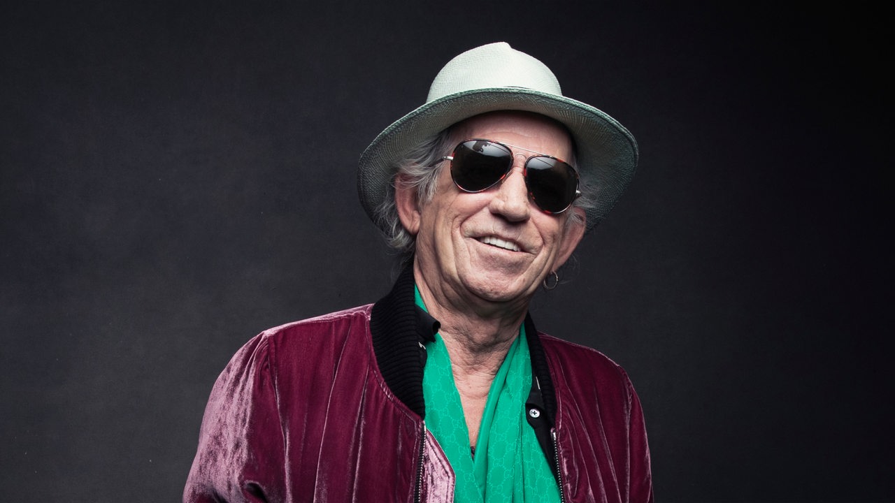 Rolling Stones-Gitarrist Keith Richards mit Sonnenbrille und Hut lacht in die Kamera