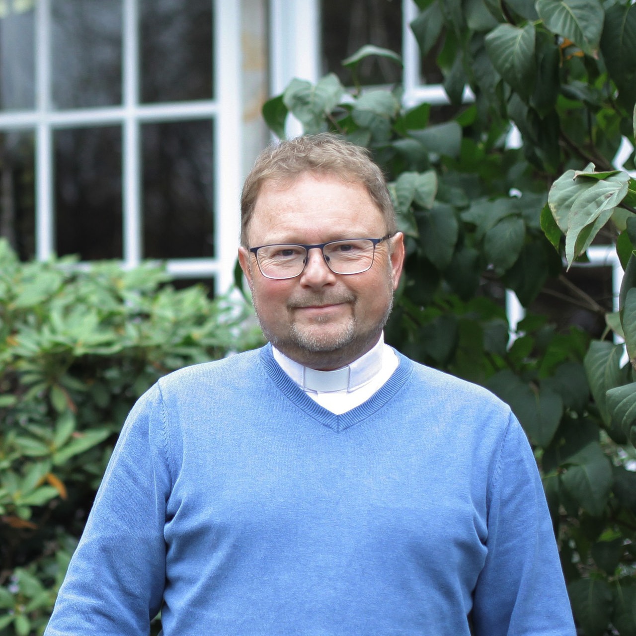 Pastor Andreas Hamburg steht vor Büschen bei der Markusgemeinde in Bremen Arsten